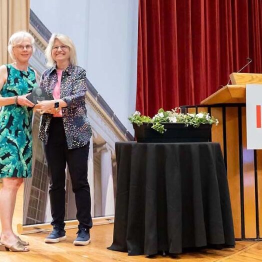 Kathleen Monagle and MIT President Sally Kornbluth pose together on a stage. They both hold a Collier Medal.
